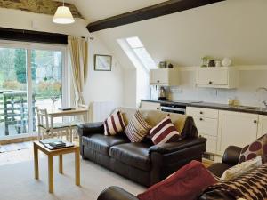 a living room with a leather couch and a kitchen at The Coach House - Hw7782 in Llanarmon Dyffryn-Ceiriog