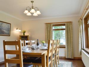ein Esszimmer mit einem Tisch, Stühlen und einem Fenster in der Unterkunft Pinewood in Gairlochy