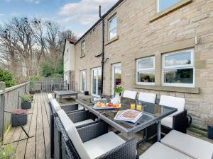 a patio with a table and chairs on a deck at Graces Dairy in Wooler
