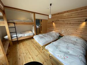 a room with two beds and a wooden wall at Yubaba House Downtown Apartments in Nozawa Onsen