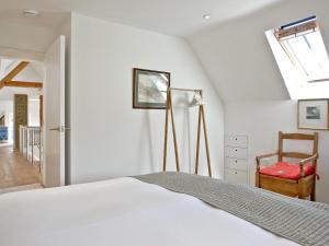 1 dormitorio con cama, ventana y silla en Antells Farm Barn en Sturminster Newton