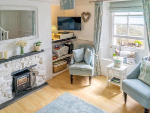 a living room with a fireplace and a chair at Tranquility - 28004 in Mevagissey