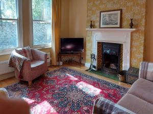 a living room with a fireplace and a red rug at Squirrel Cottage in Thornton Dale