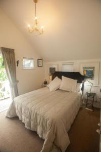 a bedroom with a large bed with a chandelier at Dove Cottage in Auckland