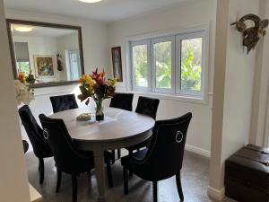 a dining room table with chairs and a vase of flowers at Dove Cottage in Auckland