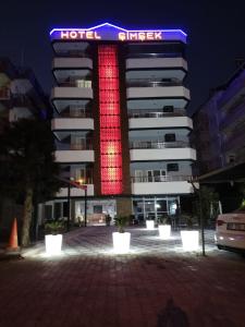 a hotel with a red lighted sign in front of a building at Hotel Simsek in Finike