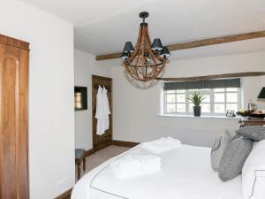 a bedroom with a white bed and a chandelier at Narrowgates Cottage in Barrowford