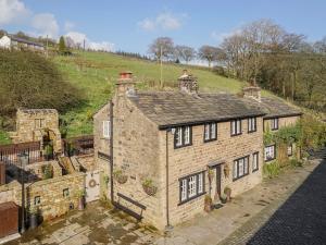 an old brick house with a hill in the background at Narrowgates Cottage in Barrowford
