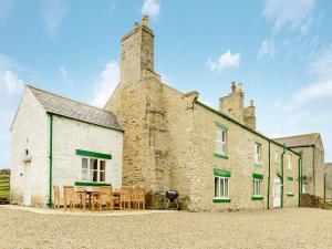 - un vieux bâtiment en pierre avec une table et des chaises à l'extérieur dans l'établissement Backstone Bank Farmhouse, à Wolsingham