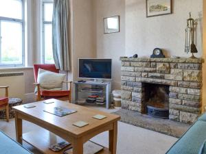 a living room with a stone fireplace and a tv at The Castaway in Mundesley