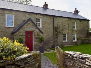 an old stone house with a red door at Fountain Hill in Eglwyswrw