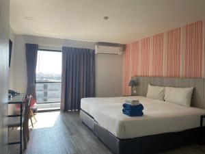 a hotel room with a bed and a window at Embryo Hotel  in Pattaya Central