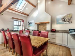 a kitchen with a wooden table and red chairs at Stack View Cottage in Holyhead