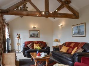 ein Wohnzimmer mit 2 Ledersofas und einem Tisch in der Unterkunft Brampton Hill Farm Cottage in Madley