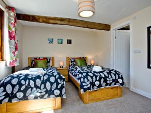 a bedroom with two beds and a window at Blackbird Cottage in Kings Nympton