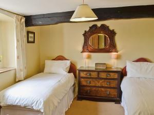 a bedroom with two beds and a dresser with a mirror at Little Knott in High Nibthwaite