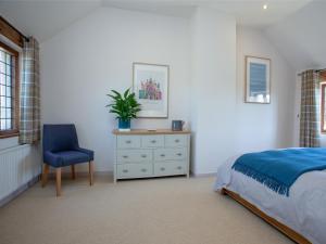 1 dormitorio con cama, silla y vestidor en Little Nymett en North Tawton