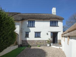 a white house with a thatched roof at Little Nymett in North Tawton