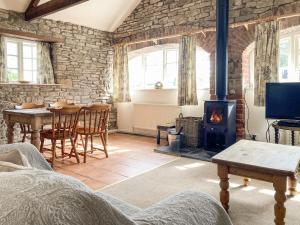 a living room with a wood stove and a table at Dairy Cottage in Abergavenny