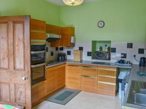 a kitchen with wooden cabinets and a clock on the wall at Millford House in Hartland