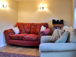 a living room with a red couch and a chair at The Cot in Chalford