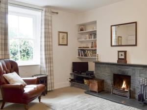 a living room with a fireplace and a chair at Roundhill Cottages 1 in Grasmere