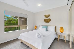 a white bedroom with a bed and a window at Vacanze A Casa - Resort Just Minutes From The CBD in Cairns North