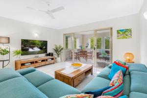 a living room with a blue couch and a table at Vacanze A Casa - Resort Just Minutes From The CBD in Cairns North