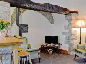sala de estar con chimenea de piedra, mesa y sillas en Tre Fardre, en Kinmel