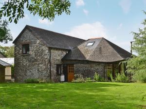 una antigua casa de piedra con césped verde en Oak Cottage en Woolfardisworthy