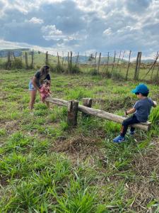 una mujer y un niño sentados en una valla en Cantinho dos sonhos, en Paraibuna 2 fotos más