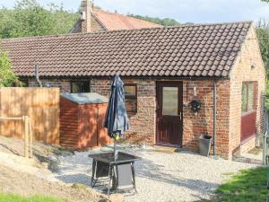 a brick house with an umbrella in front of it at Bellwood House Annexe in Felixkirk