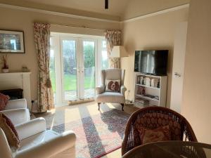 uma sala de estar com um sofá e uma cadeira e uma televisão em Tarandoun Cottage em Helensburgh