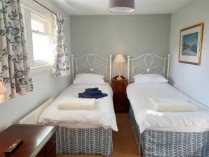 a bedroom with two beds and a desk and a window at Tarandoun Cottage in Helensburgh