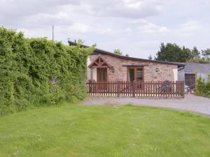 a stone house with a wooden fence and a yard at Orchard View Barn in Plymtree