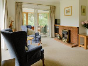 sala de estar con sillas y chimenea en Covert Cottage en Gasthorpe
