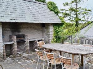 a patio with a table and chairs and a brick fireplace at Wern Y Wylan Court in Llanddona