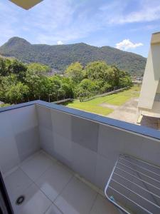 a room with a balcony with a view of a mountain at Apartamento Martin de Sá in Caraguatatuba