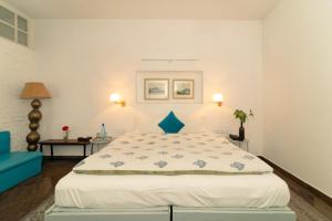een slaapkamer met een groot wit bed met blauwe accenten bij Mango Tree Courtyard Dehradun in Dehradun