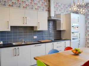 una cocina con armarios blancos y una mesa con un bol de fruta en South Cliff Sands Ii en Scarborough