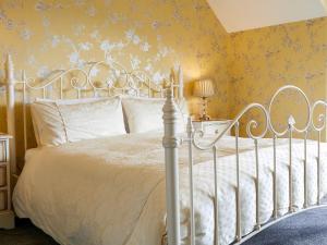 1 dormitorio con cama blanca y papel pintado de color amarillo en South Cliff Sands Ii en Scarborough
