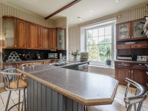 cocina con armarios de madera y encimera en Holly House, en Pooley Bridge