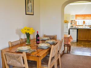 a dining room table with chairs and a bottle of wine at Eaton Barn in Burmarsh