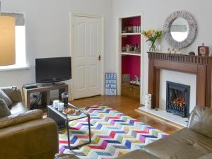 a living room with a couch and a fireplace at Naters Apartment in Cullercoats