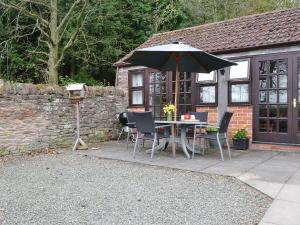 eine Terrasse mit einem Tisch, Stühlen und einem Sonnenschirm in der Unterkunft Brampton Hill Farm Cottage in Madley