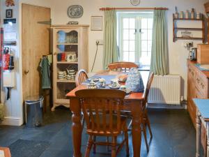 a dining room with a table and chairs and a kitchen at Downhouse Cottage in Delabole