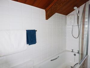 a white bathroom with a shower and a bath tub at Downhouse Cottage in Delabole