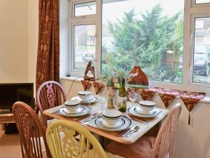 a dining room table with chairs and a large window at Cedars in Fordwich