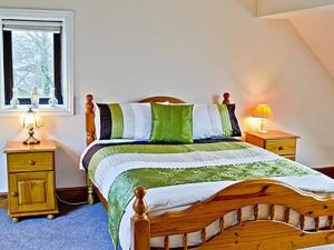 a bedroom with a wooden bed with green and white sheets at Myton House in Thornton Steward