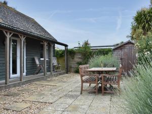 a patio with a table and chairs and a house at Cockle Cottage in Middleton-on-Sea